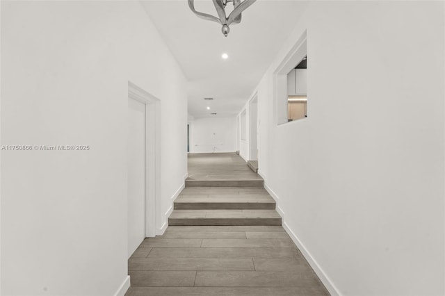 hallway featuring baseboards, wood finished floors, and recessed lighting