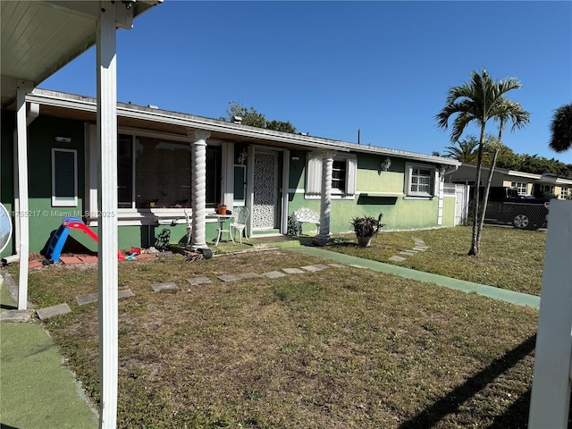 view of front of property featuring stucco siding, a front yard, and fence