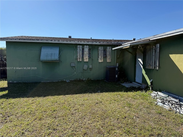 exterior space with central air condition unit, a lawn, and stucco siding