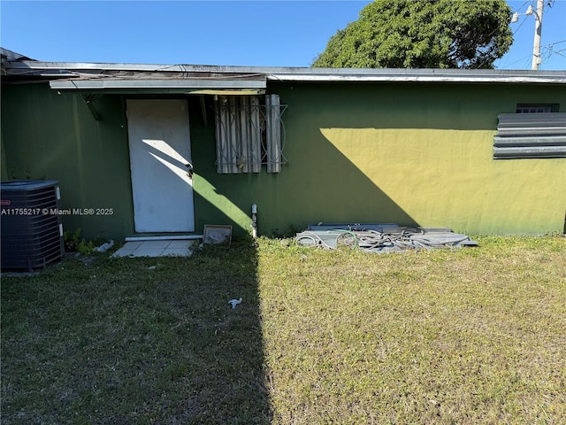 view of home's exterior with stucco siding, a lawn, and central AC