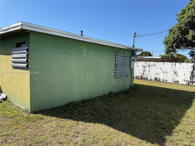 view of side of home featuring a lawn and fence