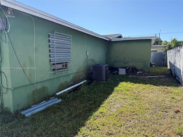 view of home's exterior featuring central air condition unit, a lawn, and fence