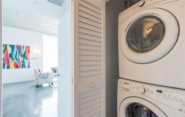 laundry area featuring baseboards, laundry area, visible vents, and stacked washer / drying machine