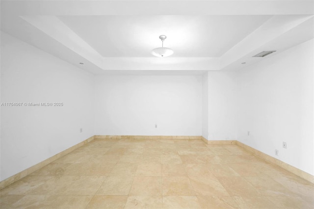 spare room featuring visible vents, baseboards, and a raised ceiling