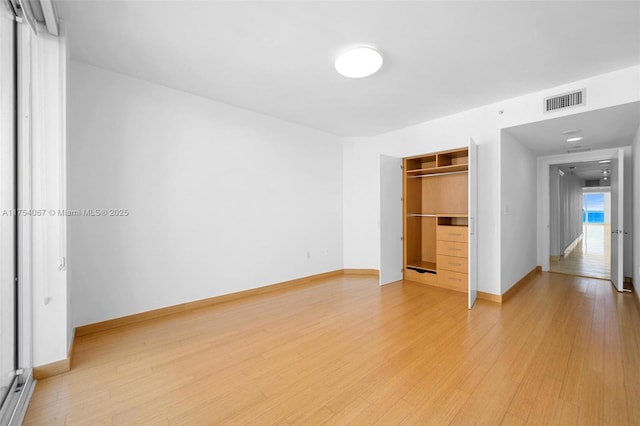 unfurnished bedroom with light wood-style floors, baseboards, visible vents, and a closet