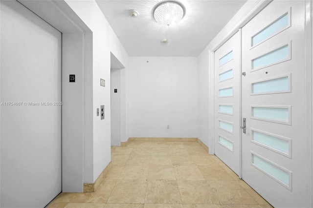 hallway featuring elevator and baseboards