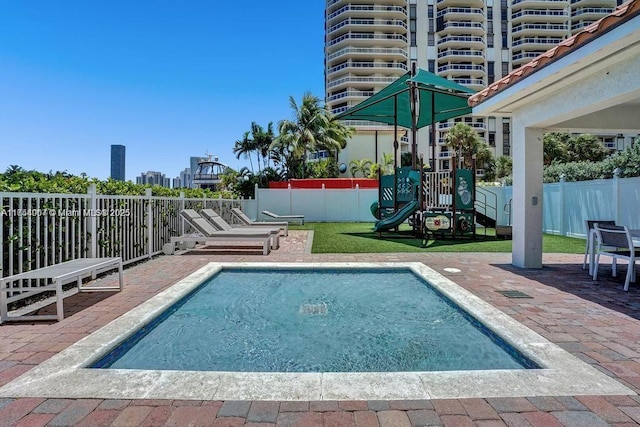 view of swimming pool featuring a patio area, playground community, and fence