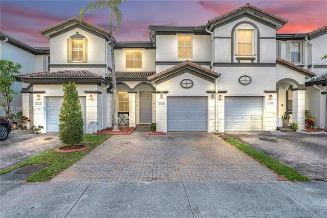 view of front facade featuring driveway, a tiled roof, a garage, and stucco siding