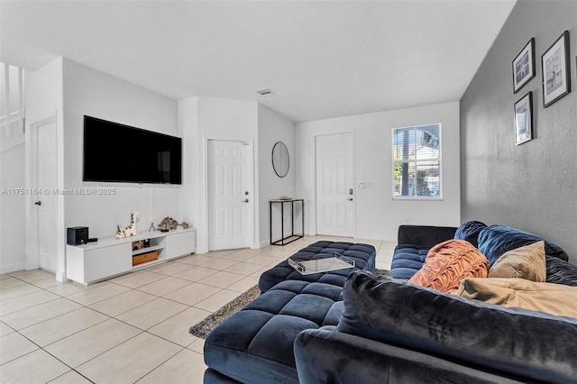 living room with light tile patterned floors, visible vents, and baseboards