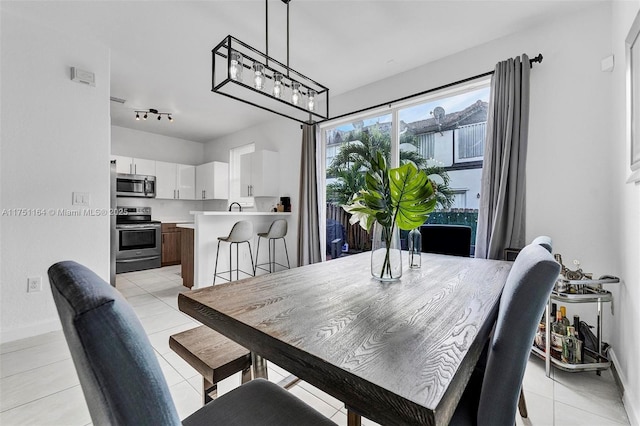 dining space with baseboards and light tile patterned floors