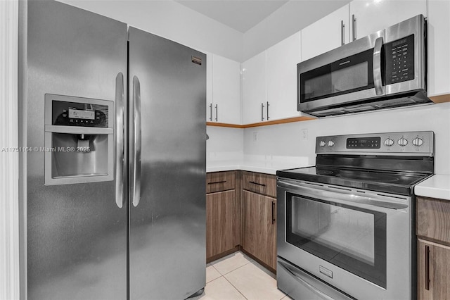 kitchen featuring light countertops, appliances with stainless steel finishes, light tile patterned flooring, and white cabinets