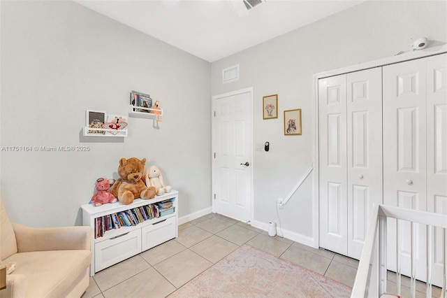 bedroom with light tile patterned floors, baseboards, visible vents, and a closet