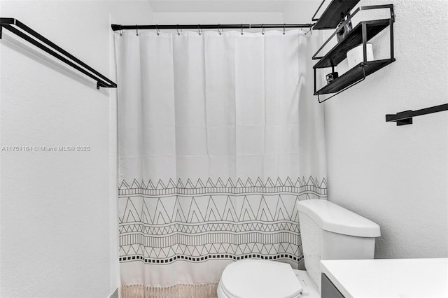 bathroom with curtained shower, a textured wall, and toilet