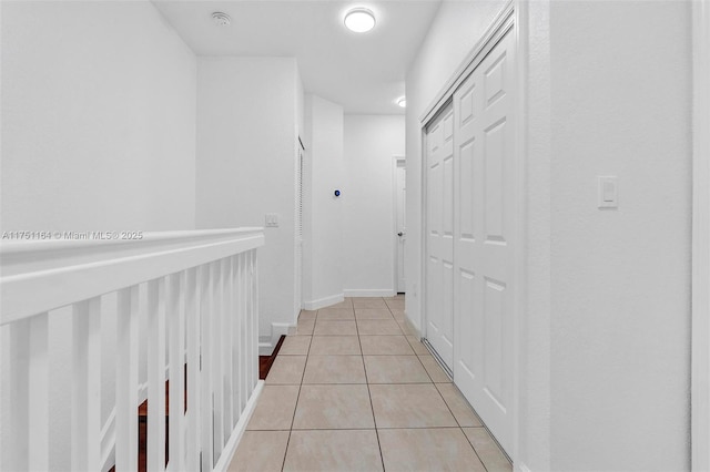 corridor with light tile patterned floors and baseboards