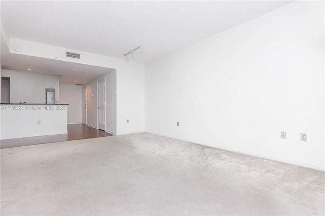 unfurnished room featuring carpet, visible vents, and rail lighting