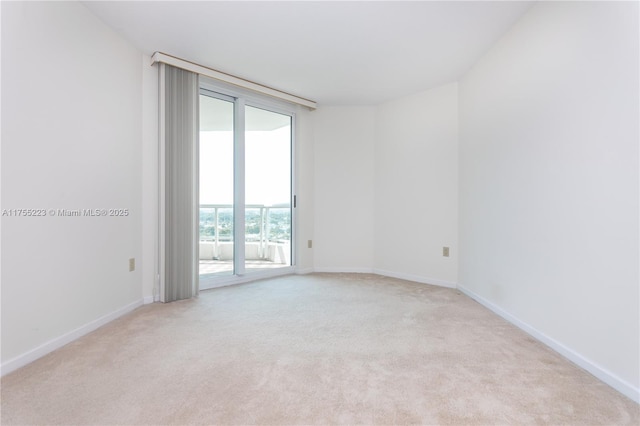 spare room with baseboards and light colored carpet