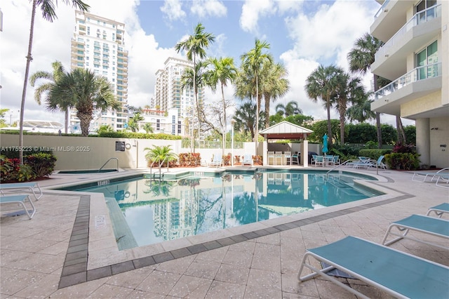 community pool featuring a gazebo, a patio area, fence, and a city view