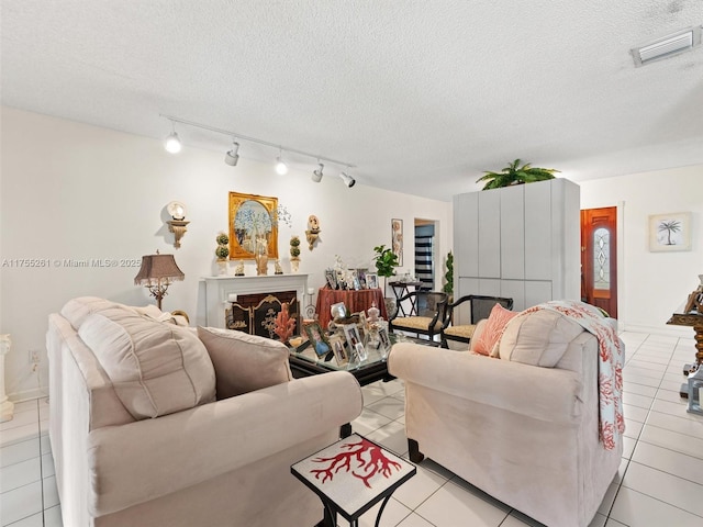 living area with a textured ceiling, light tile patterned flooring, a fireplace, and visible vents