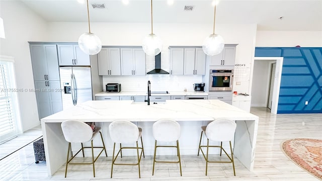 kitchen featuring appliances with stainless steel finishes, visible vents, a large island, and wall chimney exhaust hood