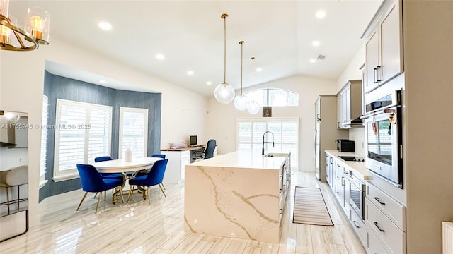 kitchen with a kitchen island with sink, black electric cooktop, a sink, stainless steel oven, and vaulted ceiling