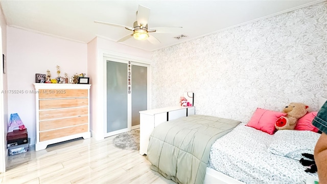 bedroom with visible vents, ceiling fan, ornamental molding, light wood-type flooring, and a closet