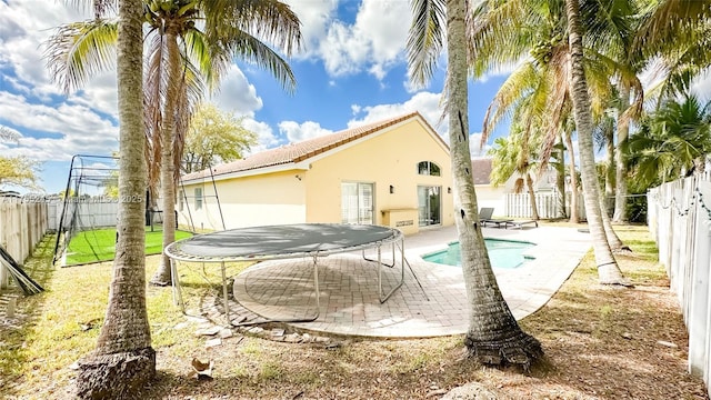 back of property featuring a fenced backyard, a fenced in pool, stucco siding, a trampoline, and a patio area