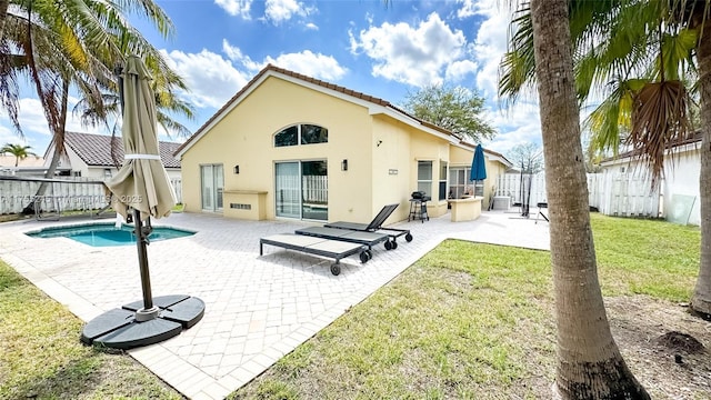 rear view of house with a fenced in pool, a lawn, a fenced backyard, a patio area, and stucco siding