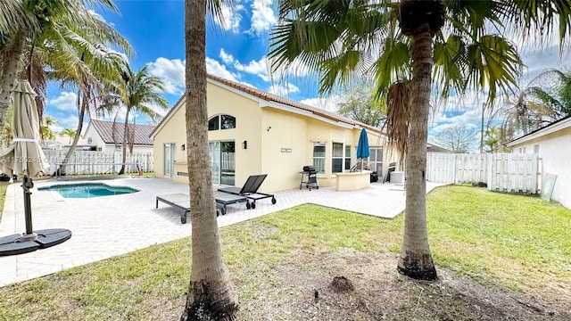 rear view of house featuring a lawn, a patio area, a fenced backyard, and stucco siding