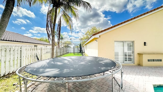 view of patio featuring a trampoline and a fenced backyard