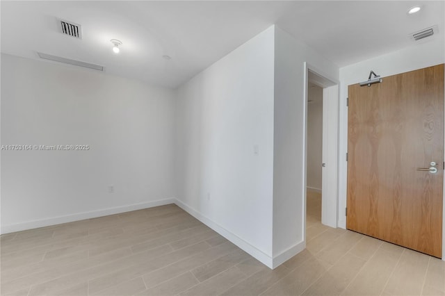 spare room with visible vents, light wood finished floors, and baseboards