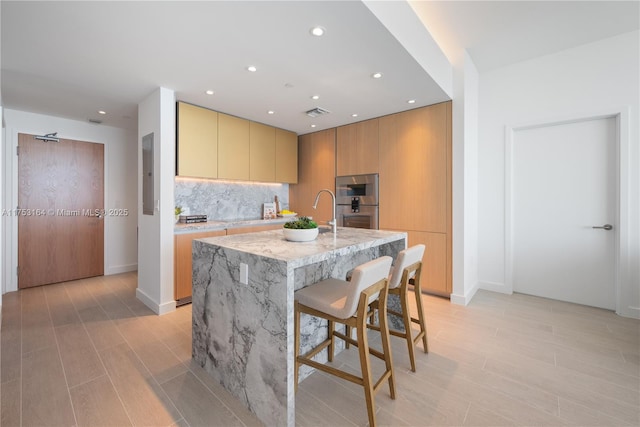 500 Alton Unit 3304, Miami Beach, FL 33139 - kitchen with modern cabinets, recessed lighting, backsplash, light stone countertops, and an island with sink