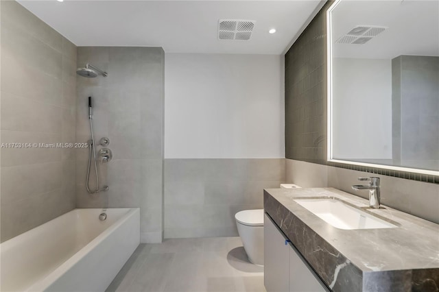 bathroom with visible vents, tile walls, toilet, and vanity