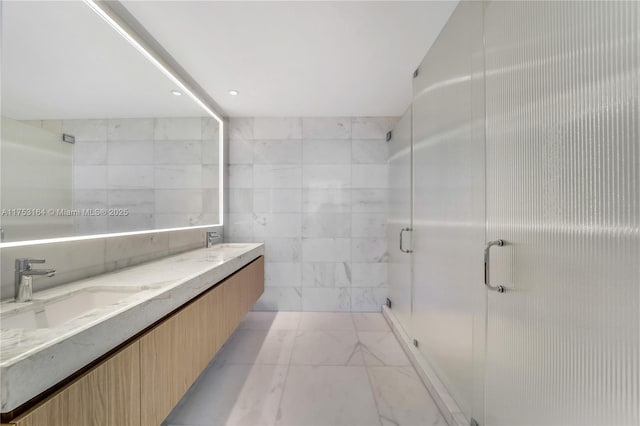 full bathroom featuring a stall shower, a sink, tile walls, and double vanity