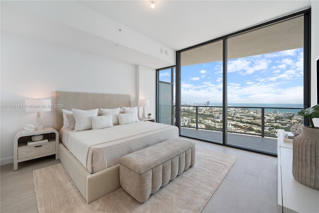 500 Alton Unit 3304, Miami Beach, FL 33139 - bedroom featuring a wall of windows, multiple windows, access to exterior, light wood-style floors, and a water view