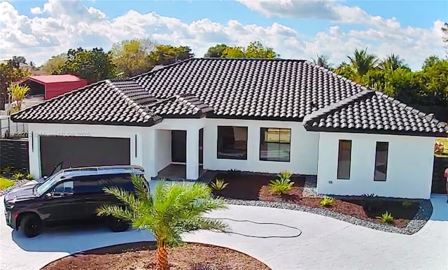 view of front of house featuring a tiled roof, a garage, driveway, and stucco siding