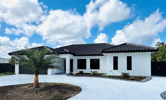 view of front facade featuring curved driveway, a tile roof, a garage, and stucco siding