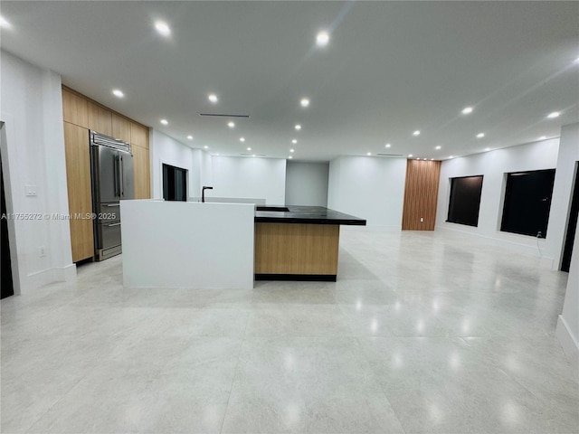 kitchen with a spacious island, recessed lighting, built in fridge, modern cabinets, and open floor plan