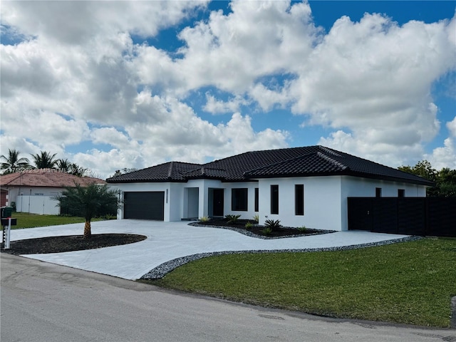 view of front of house featuring stucco siding, driveway, a front lawn, and a garage