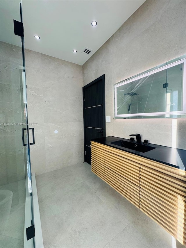 bathroom featuring visible vents, recessed lighting, a stall shower, and tile walls