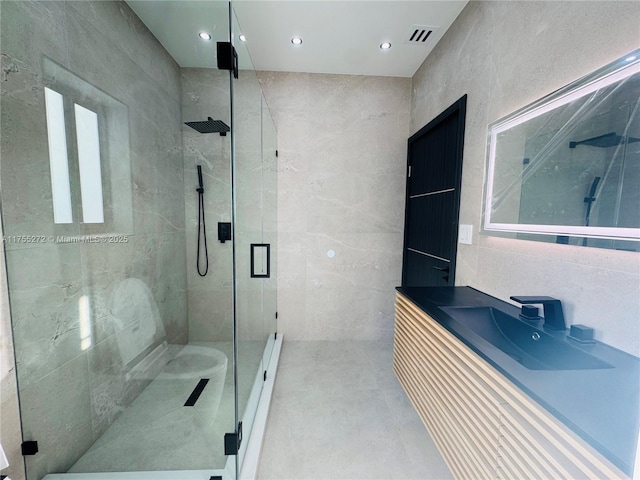 bathroom with visible vents, a stall shower, tile walls, and vanity