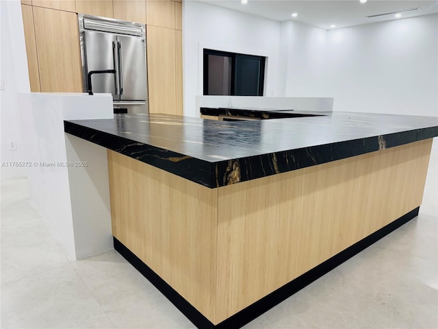 kitchen with light brown cabinets, dark stone counters, high quality fridge, recessed lighting, and modern cabinets