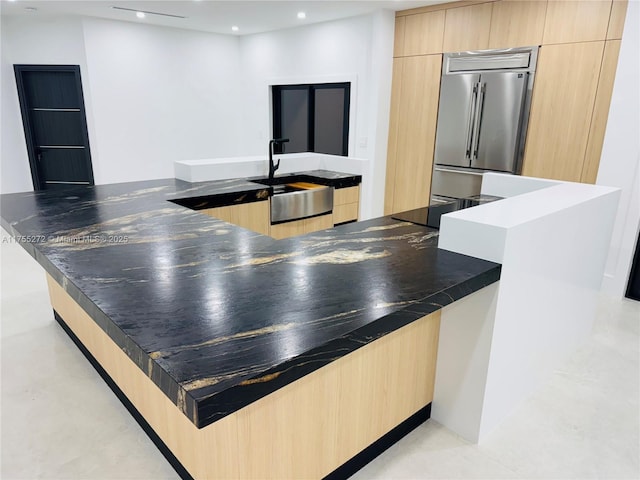 kitchen with modern cabinets, stainless steel built in refrigerator, light brown cabinetry, a sink, and recessed lighting