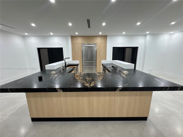 kitchen with light brown cabinets, recessed lighting, a large island with sink, high end fridge, and modern cabinets