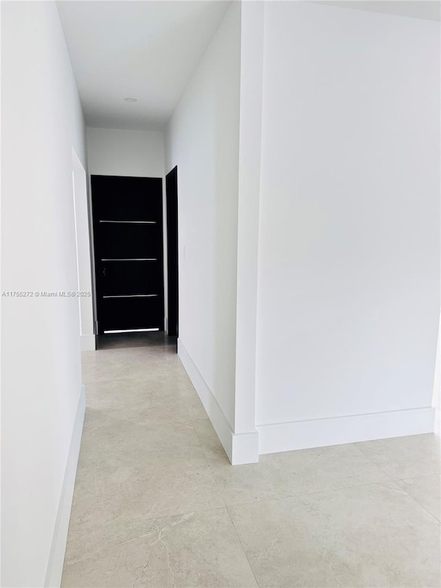 corridor featuring baseboards and finished concrete floors