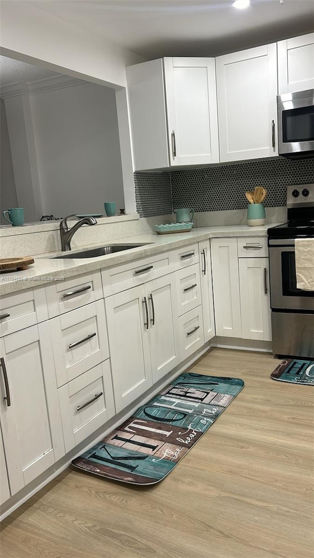 kitchen featuring light countertops, appliances with stainless steel finishes, light wood-type flooring, and a sink