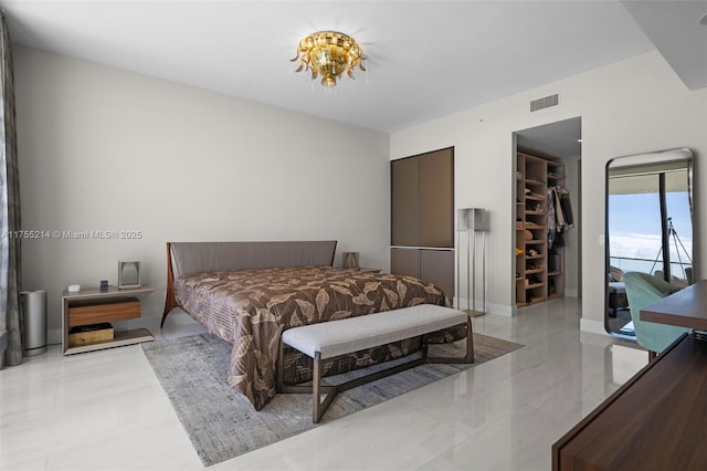 bedroom with a walk in closet, a closet, visible vents, and baseboards