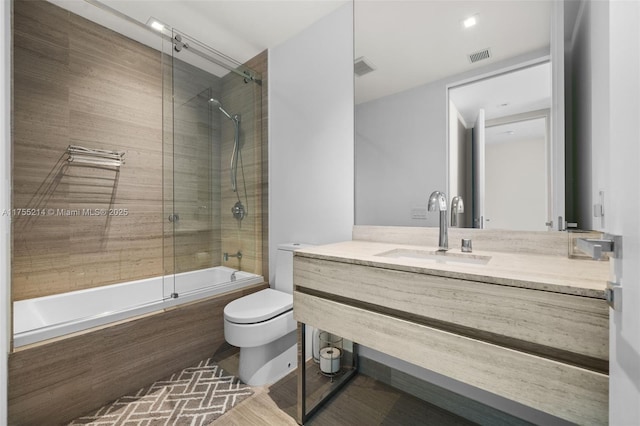 bathroom featuring toilet, vanity, visible vents, and tiled shower / bath combo