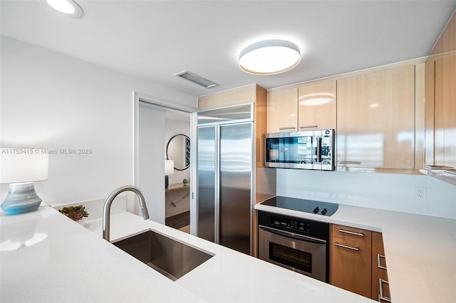 kitchen with stainless steel appliances, light countertops, a sink, and visible vents