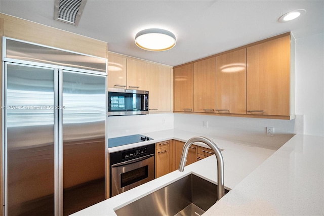 kitchen with recessed lighting, stainless steel appliances, a sink, visible vents, and light brown cabinetry