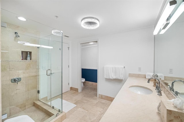 bathroom with toilet, a stall shower, baseboards, and vanity